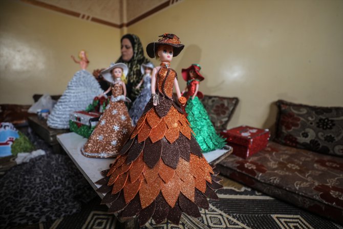 Filistinli Hena oyuncak bebekleri renkli kartonlarla giydiriyor