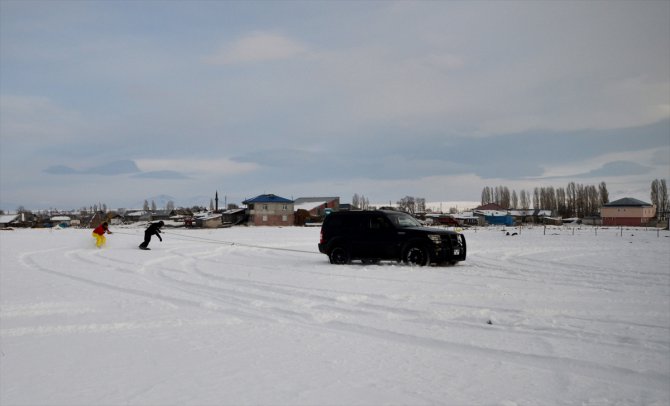 Köyde yaşayan gençlerden arazi aracıyla karda snowboard