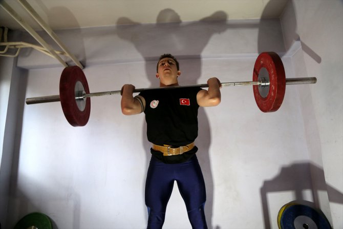 Dünya şampiyonu halterci, kapıcı dairesinde hazırlıklarını sürdürüyor
