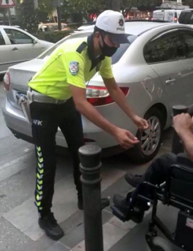 Geçide park edilen otomobil nedeniyle karşıya geçemeyen engellinin yardımına polis koştu
